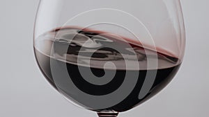 Red wine swirling glass slow motion. Gourmet alcohol drink waving in wineglass.