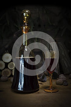 Red Wine Vintage Bottle and Glasses Resting On Wooden Table Against Christmas Background With Wood logs and Pine Branches