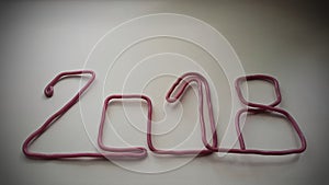 the red wire forms the number 2018 on a warm white background