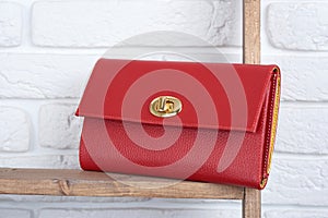 Red woman s leather clutch on the white wall background