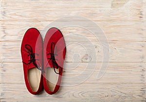 Red women`s shoes oxfords on a light wooden background.