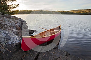 Red wood canoe on rocky island in the Boundary Waters on a bright autumn morning
