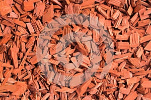 Red wood chips. Natural texture background of red wooden pieces of tree bark. Wood chips, mulch for gardening or natural themes.