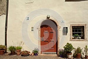 Red wood, door, barred window, of first floor home, in Fai della Paganella, Italy