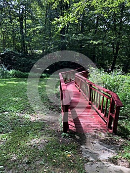 Red wooden bridge stretches towards the forest woods