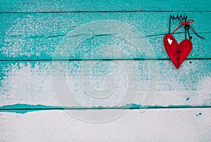 Red wooden broken heart hanging on sandy turquoise sign