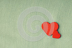 Red wooden decorative hearts on gray cloth background.