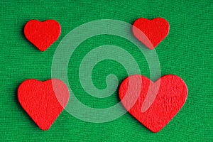 Red wooden decorative hearts on green cloth background