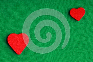 Red wooden decorative hearts on green cloth background
