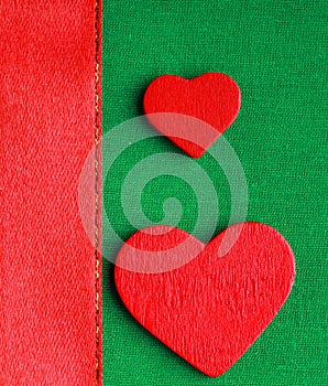 Red wooden decorative hearts on green cloth background