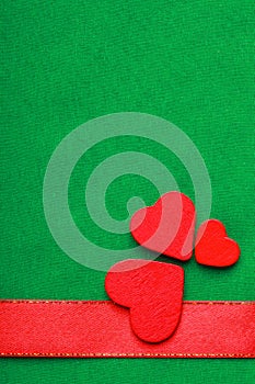 Red wooden decorative hearts on green cloth background