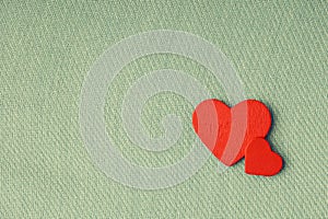 Red wooden decorative hearts on green cloth background.