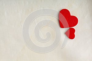 Red wooden decorative hearts on white cloth background.