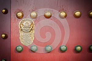 Red wooden door with golden lion figure at the Forbidden City, Beijing