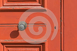 Red wooden door with keyhole, brass doorknob with shadow