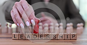 Red wooden figurine standing above others and word leadership