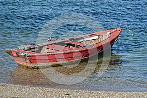 Red wooden fishing boat moored on the shore