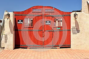 Red wooden gate in an adobe wall