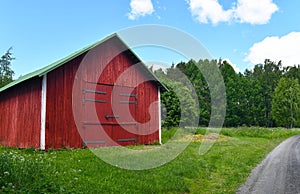 Red wooden hay barn by the narrow gravel road