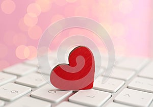 Red wooden heart on computer keyboard, closeup. Online dating