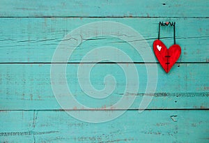 Red wooden heart hanging on turquoise background