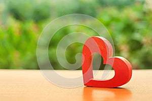 A red wooden heart on nature background. The secret of relationships and the rules of a strong family. Strong love affair. Secrets