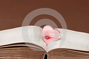 A red wooden heart on an old book