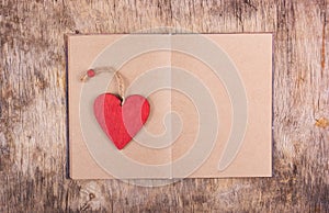 Red wooden heart and an open book with blank pages on the old wooden background. Bookmarks and Valentine of wood.