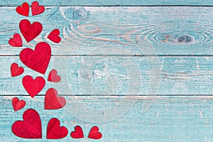 Red wooden hearts on the left border on a blue scaffold wooden background