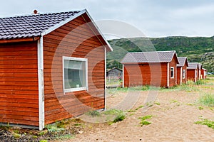 Red wooden houses on the sandy beach of the Barents Sea. Teriberka.