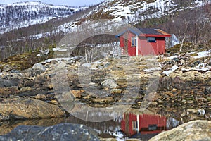 Red wooden hut on the shoreline of Stonnesbotn Fjord