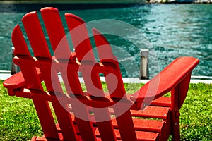 A red wooden lawn chair on the waterfront riverwalk on a sunny day