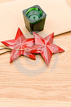 red wooden stars Christmas decoration and green candle on a wooden background