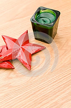 red wooden stars Christmas decoration and green candle on a wooden background