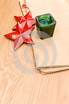 red wooden stars Christmas decoration and green candle on a wooden background