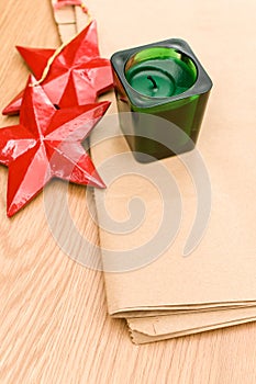 red wooden stars Christmas decoration and green candle on a wooden background