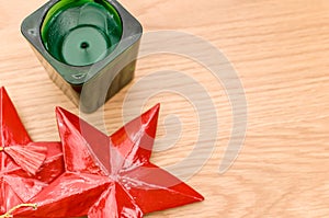 red wooden stars Christmas decoration and green candle on a wooden background