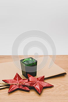 red wooden stars Christmas decoration and green candle on a wooden background