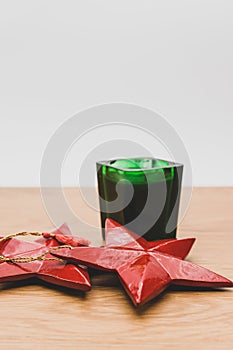 red wooden stars Christmas decoration and green candle on a wooden background