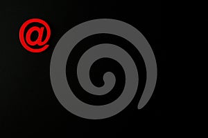 Red wooden symbol `at` on black background
