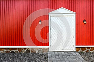 Red wooden wall and white front doors with two lamps