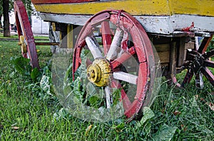 Red wooden wheel of an old cart in green grass