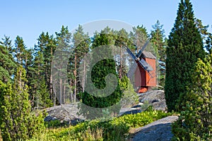 Red wooden windmill in a old vintage rural landscape at Aland islands, Finland. Jan Karlsgarden open air museum. Ethnographic park