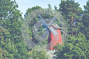 Red wooden windmill in a old vintage rural landscape at Aland islands, Finland. Jan Karlsgarden open air museum. Ethnographic park