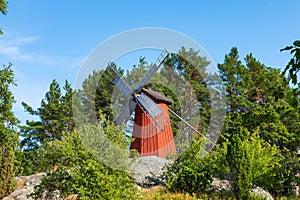 Red wooden windmill in a old vintage rural landscape at Aland islands, Finland. Jan Karlsgarden open air museum. Ethnographic park