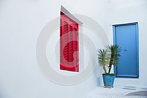 Red wooden window and cyan blue door at white wall