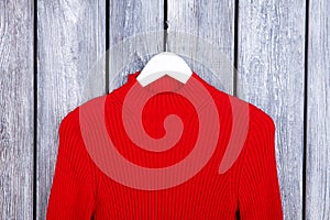 Red wool sweater on hanger close up.