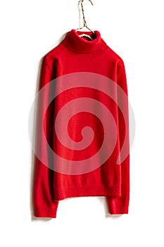 Red wool sweater hanging on clothes hanger on white background.close up