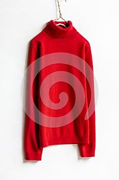 Red wool sweater hanging on clothes hanger on white background.close up