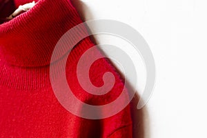 Red wool sweater hanging on clothes hanger on white background.close up